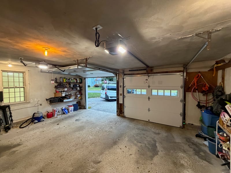 Inside the Acton garage after the install: two LiftMaster belt-drive openers on the ceiling and the new white doors with windows