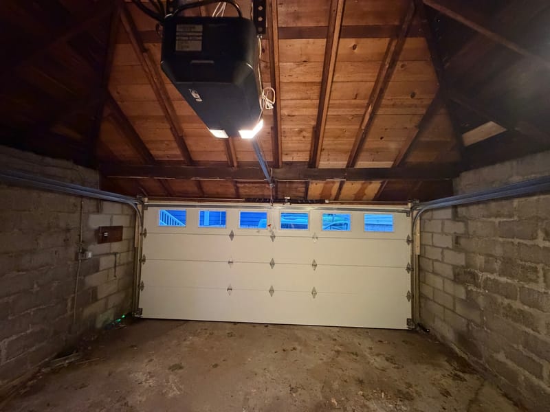 Inside the detached garage: the new white double door with its row of windows, seen at dusk