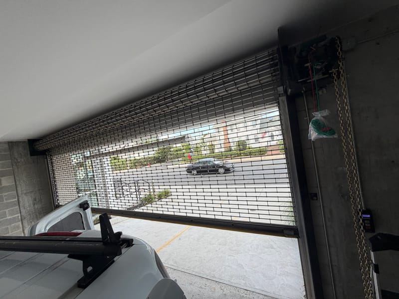 Side-mounted operator beside a rolling security grille at a parking garage